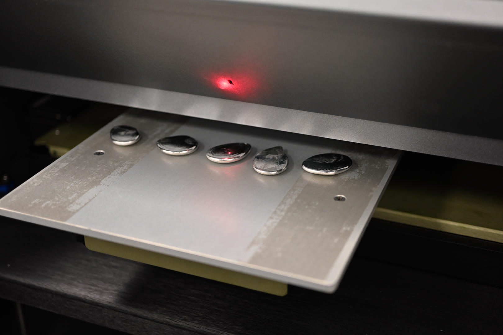 Metal samples on a tray under laser.